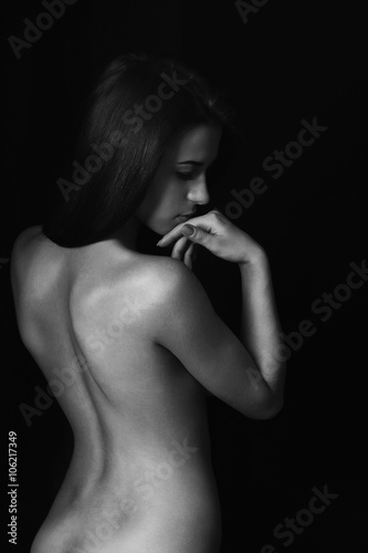 Beautiful thin naked female body perfect shape  with back view on black background  vertical picture