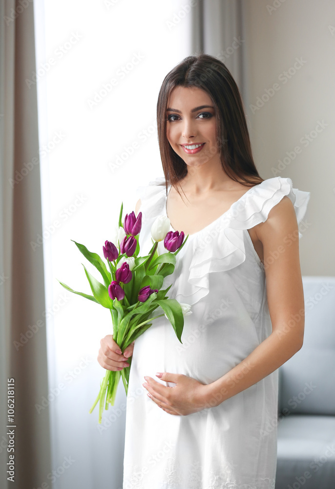 Pregnant woman with beautiful bouquet of tulips in the room Pregnant woman with beautiful bouquet of tulips in the room