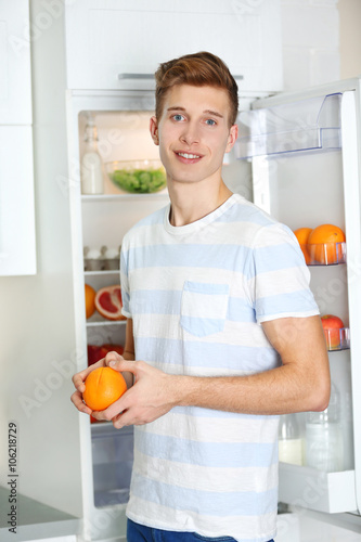 Handsome man taking food from refrigerator