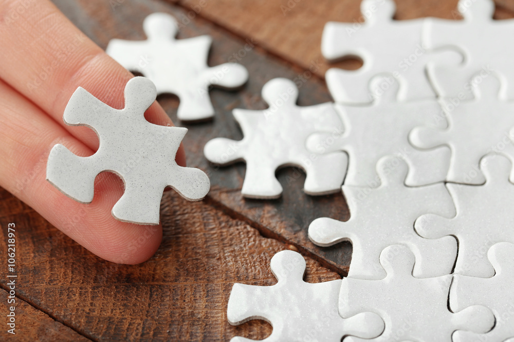 Woman playing with jigsaw puzzle on wooden table Woman playing with jigsaw puzzle on wooden table