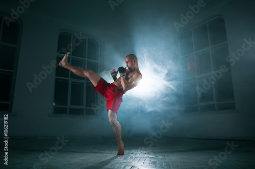 Canvas Print The young man kickboxing in blue smoke