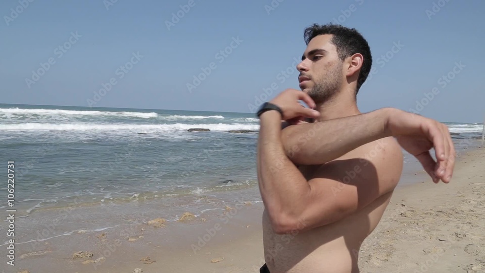 Muscular male doing stretching workout on the beach Muscular male doing stretching workout on the beach