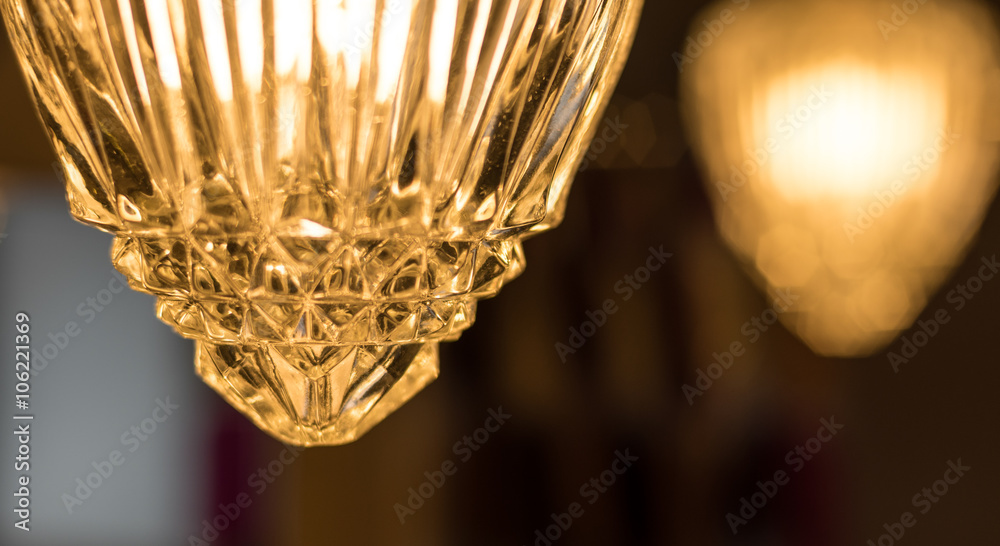 Detail of a crystal style glass cover which adorns a hanging chain link, swag style lamp in a bathroom.  Fashionable lighting for the home.