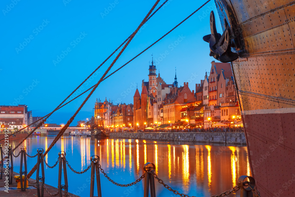 Fototapeta premium Mariacka Gate at the Dlugie Pobrzeze and Motlawa River in old town of Gdansk at night, Poland