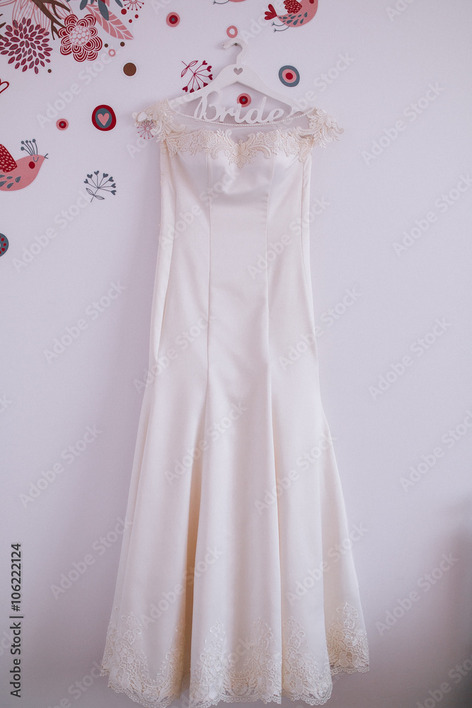 The perfect wedding dress with a full skirt on a hanger in the room The perfect wedding dress with a full skirt on a hanger in the room