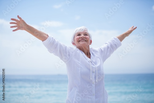 Senior woman with arms outstretched by sea