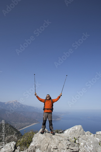 A traveler stands on top of a mountain and looks out to sea.