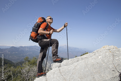 A traveler stands on top of a mountain and looks out to sea.