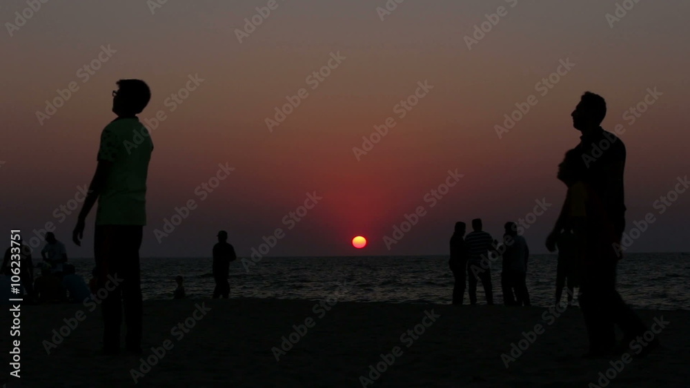 People resting on the beach at sunset People resting on the beach at sunset
