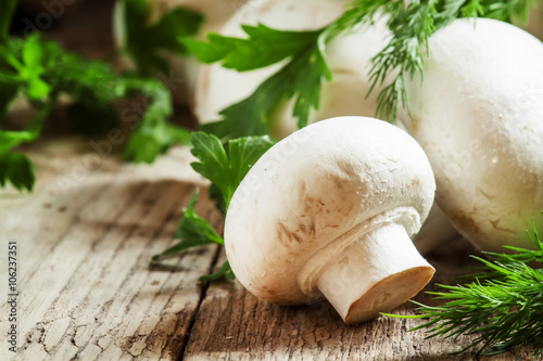 White mushrooms champignons, dill, parsley, old wooden table, ru