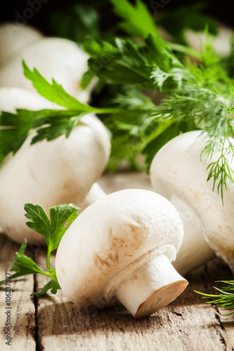 White mushrooms champignons, dill, parsley, old wooden table, ru