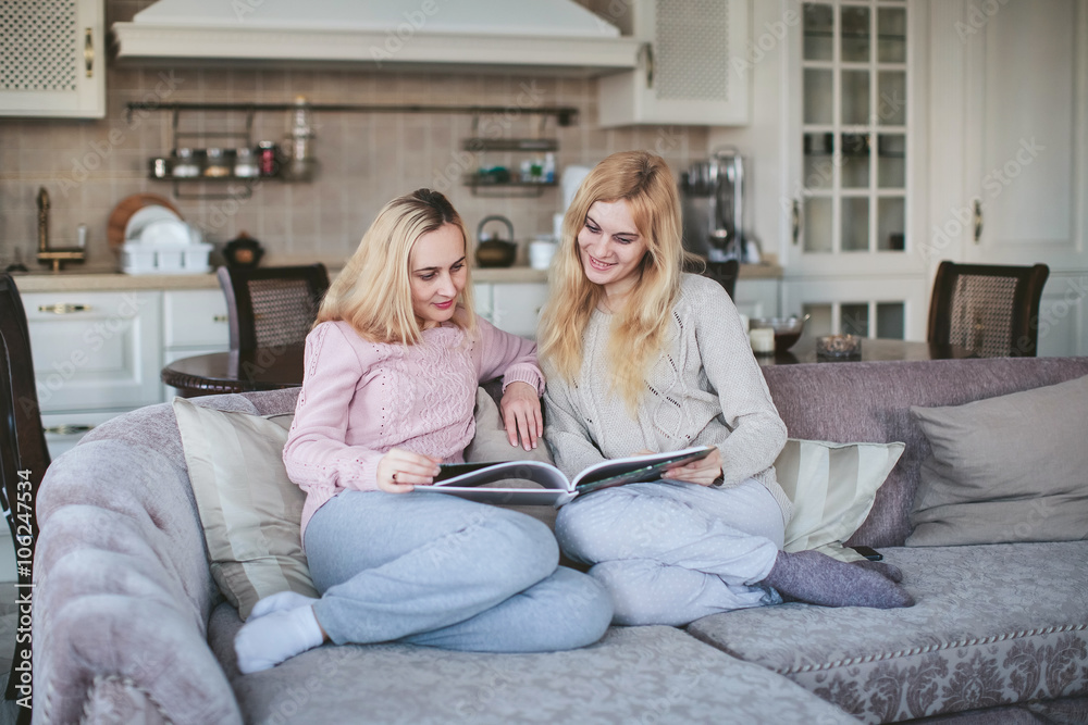 Two girls look a photo album on the sofa