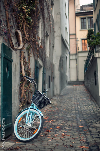 ladies bicycle with basket parked on the street on old european town © goami