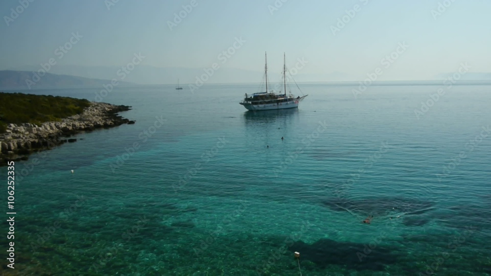Aerial view of swimming people in front docked sailing boat in the bay.
Aerial view of swimming people in front docked sailing boat in the bay.
