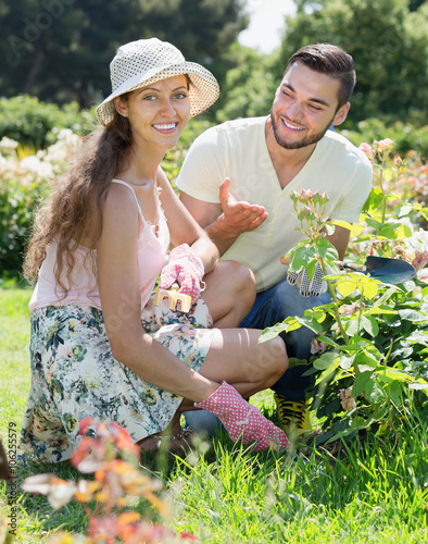 Smiling family in gloves planting flowers photo