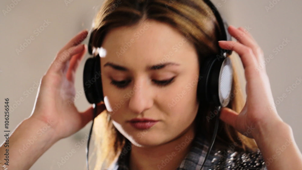 Young beautiful woman lying on the sofa and listening music in her headphones on the living room. Young beautiful woman lying on the sofa and listening music in her headphones on the living room.