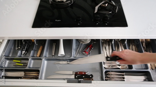 Close up of female hands opening kitchen cabinet door and taking the biggest knife from their.