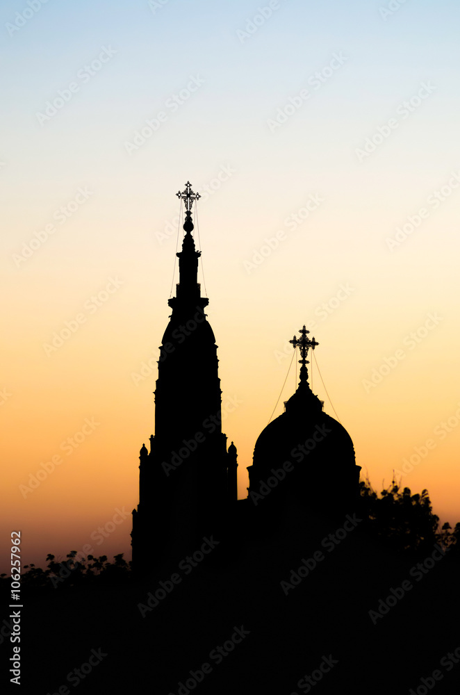 Two church silhouettes against sunset sky.