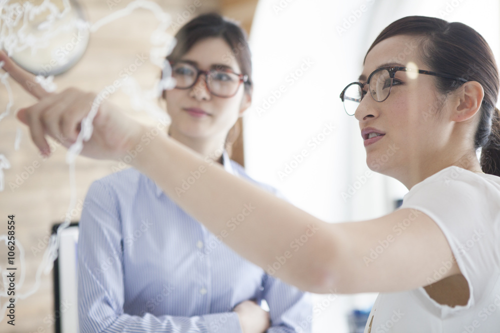 Women are talking while pointing to the map of the world Women are talking while pointing to the map of the world