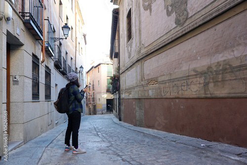 Asian woman traveler using her phone in the small alley at Toled