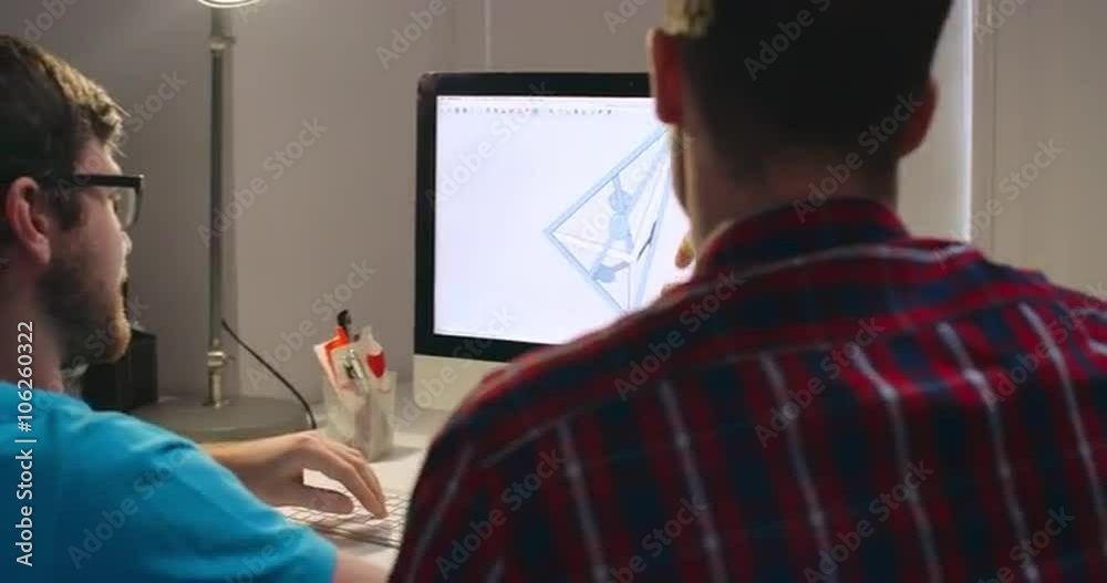 Two engineers using computer software to design 3D models and discussing them 