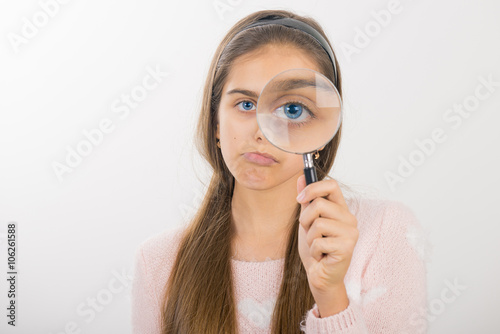 Beautiful girl looking through a magnifying glass