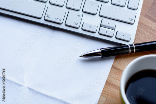 Office desk with keyboard, coffee, pen and paper