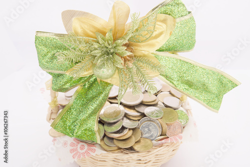 Stack of gold coins in basket with green ribbon