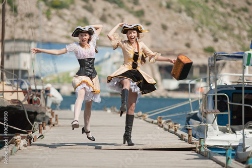 Two girls in pirate costumes are jumping