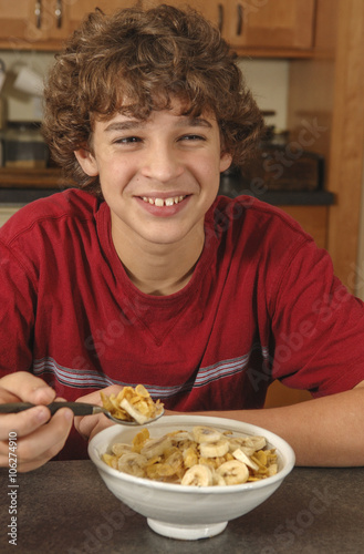 Cute teenage boy enjoying cereal ay breakfast