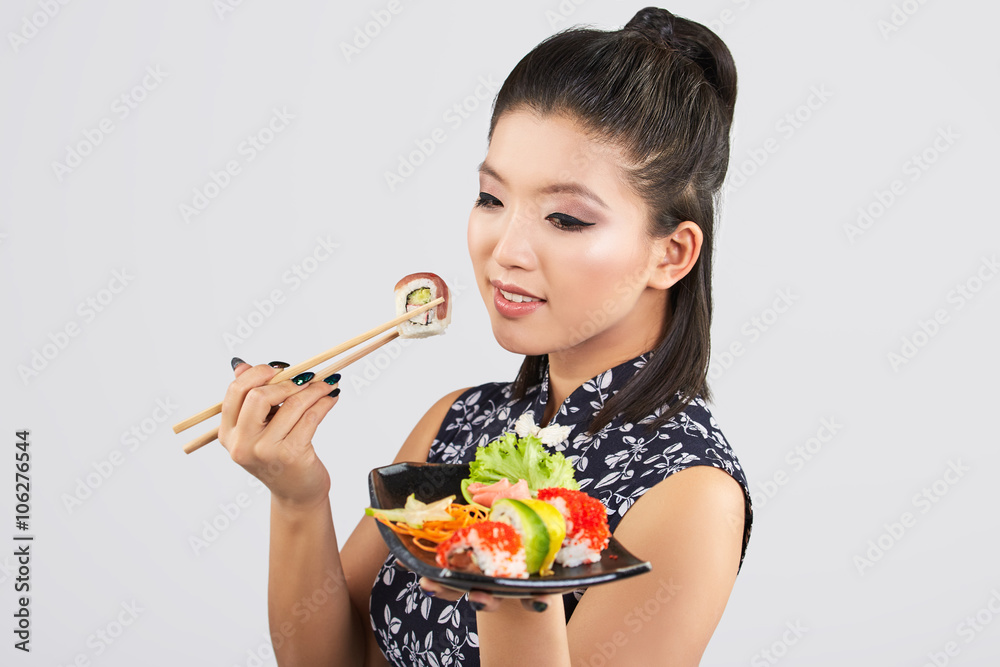 Young beautiful asian woman eating sushi with chopsticks, Young beautiful asian woman eating sushi with chopsticks,