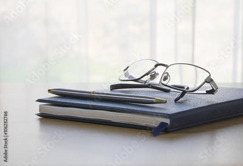 Glasses and pen on a book