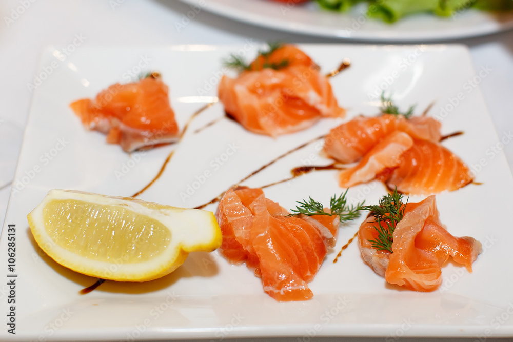 Sliced pieces of salmon and lemon on a white plate