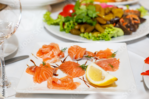 Sliced pieces of salmon and lemon on a white plate