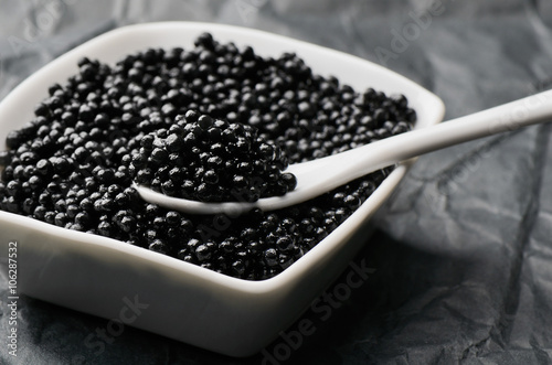 spoon of black caviar in a white bowl
