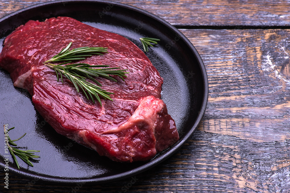 Raw beef steak with herbs and rosemary, fresh juicy on a wooden table background. Seleсtive focus Raw beef steak with herbs and rosemary, fresh juicy on a wooden table background. Seleсtive focus