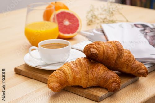 Delicious croissant with a cup of coffee and a glass of orange j