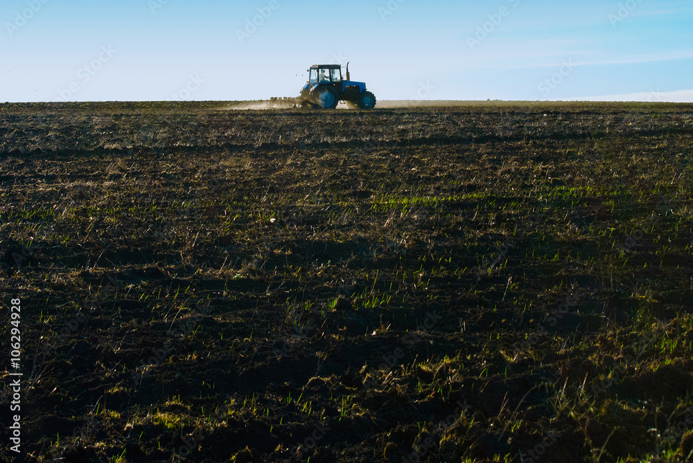Fototapeta premium Tractor plows a field in the spring before sowing campaign