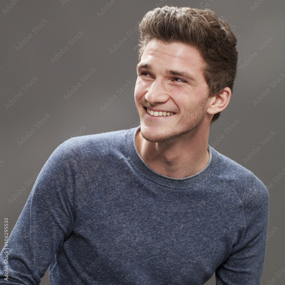 Fototapeta premium handsome smile - profile of a cool young male student looking friendly and dynamic, grey background studio..