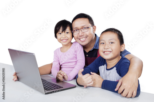 Cute children and dad with laptop on table