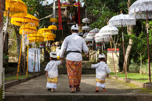 Man with children walks up the stairs during the celebration before Nyepi (Balinese Day of Silence). Ubud, Indonesia. photo