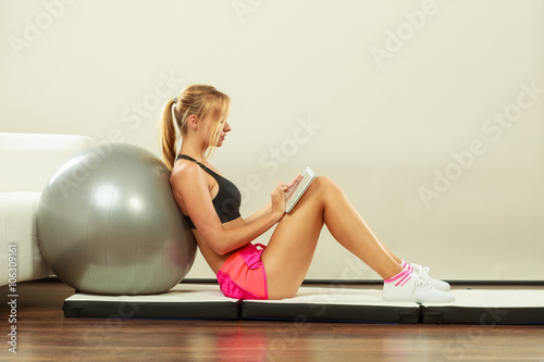 Fit woman sitting on floor with tablet pc