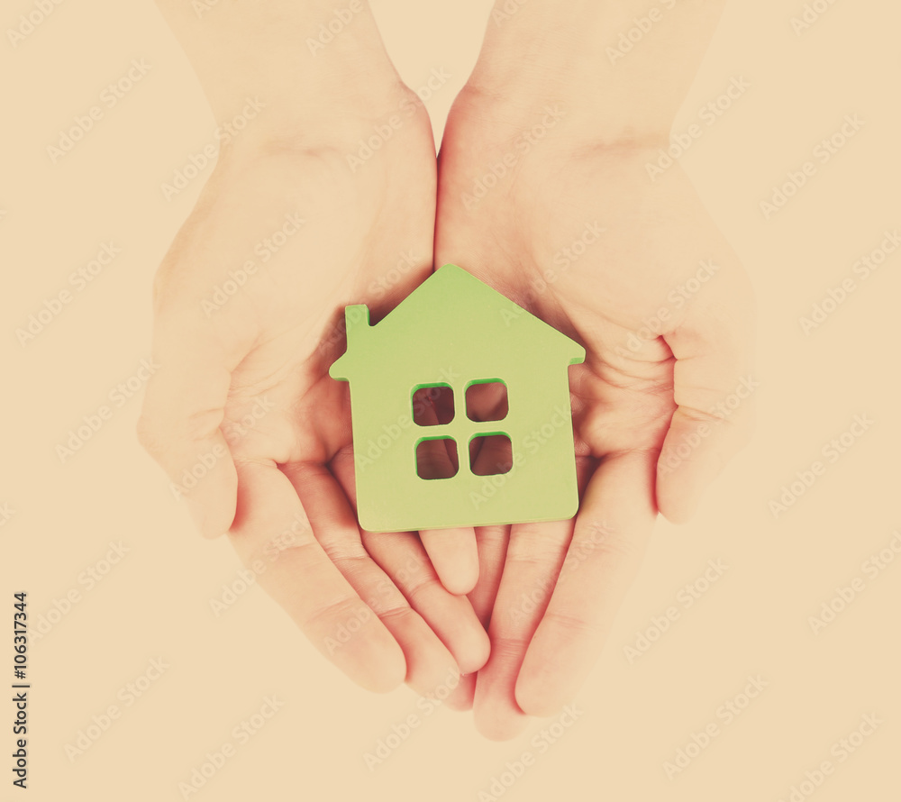 Female hands with model of house on light background Female hands with model of house on light background