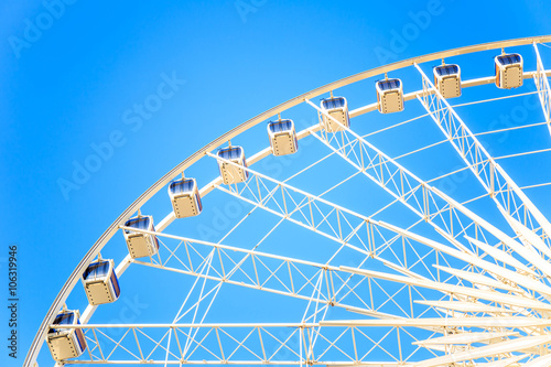 Modern ferris wheel with blue sky background.
