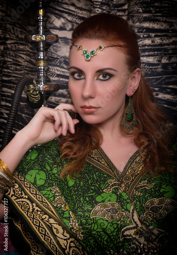 Closeup of Beautiful caucasian woman dressed in oriental style with oriental patterns on the hands and face, with numerous bracelets