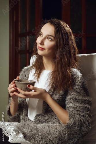 happy smiling girl with big cup of tea in her hands on armchair