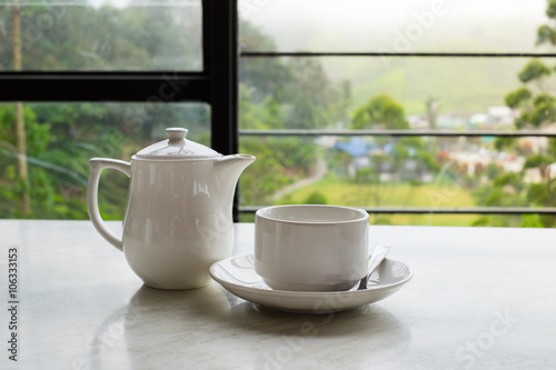 White cup of tea and teapot on white marble table
