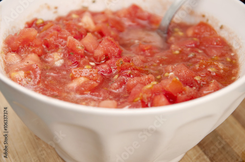 White bowl with tomato, oil, garlic, oregano, salt and pepper