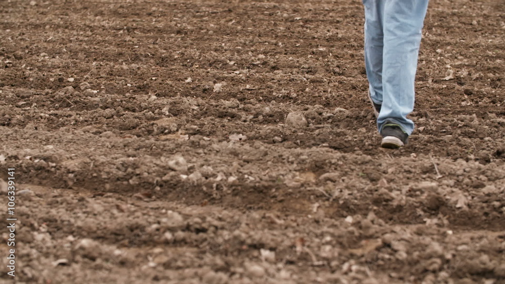 Farmer walking on farm land, planning new seeding season