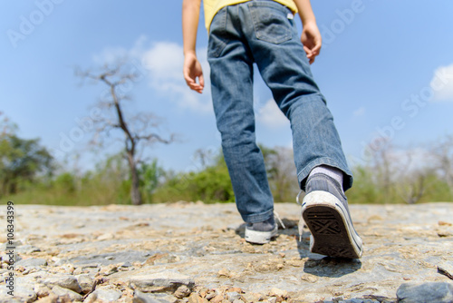 Boy walking on the rocky land.